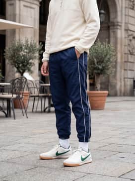 Navy blue nylon track pants with white piping, paired with a cream-colored quarter-zip fleece and high-quality white crew socks for a vintage athletic aesthetic.