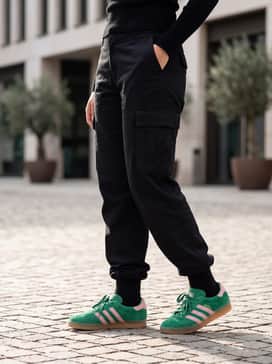 An all-black monochromatic look featuring relaxed cargo trousers and a fitted turtleneck to let the vibrant green and fuzzy texture of the sneakers stand out.