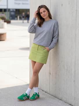 A lime green mini skirt paired with a simple grey sweatshirt and white crew socks for a playful, athletic-inspired ensemble.