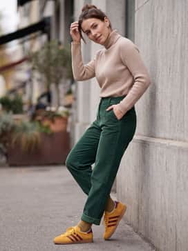Style with forest green corduroy trousers and a beige turtleneck sweater to embrace a warm, 70s-inspired color palette that highlights the rich mustard suede.