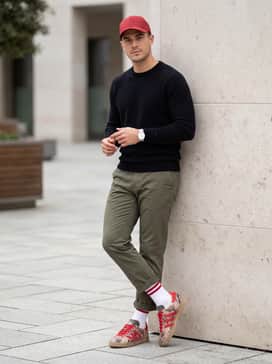 Gazelle Lux Spikeless Golf Shoes – Olive green tapered chinos worn with a black cashmere sweater and a red baseball cap to tie in the primary accent color.