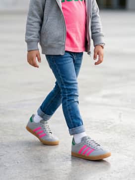 Cuffed slim-fit denim jeans paired with a neon pink graphic t-shirt and a grey zip-up hoodie to mirror the shoe's color palette.