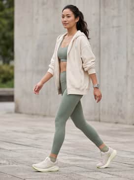 High-waisted sage green leggings paired with a matching sports bra and an oversized cream zip-up hoodie for a coordinated gym aesthetic.