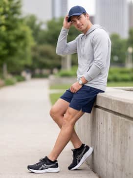Gelexcite 11 – Navy blue athletic shorts combined with a light grey performance hoodie and a sporty baseball cap, perfect for a morning coffee run or a light outdoor walk.