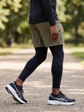 Gelexcite 11 – Black compression leggings worn under olive cargo shorts, paired with a fitted long-sleeve tech top for a layered, functional outdoor workout aesthetic.