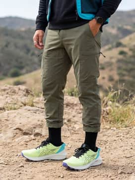 Gelexcite Trail 2 – A gorpcore-inspired ensemble featuring olive green ripstop cargo pants with bungee-cord cuffs, a black oversized technical hoodie, and a cyan-accented utility vest.