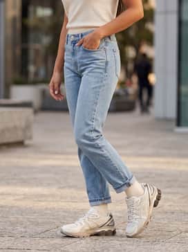 Gelkinetic Fluent – Straight-leg light-wash denim jeans with a tucked-in white t-shirt and an oversized beige trench coat for a sophisticated city look.
