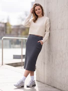Gelkinetic Fluent – A charcoal grey rib-knit midi skirt coordinated with a cropped cream sweater and white crew socks to highlight the sneakers' vintage running silhouette.
