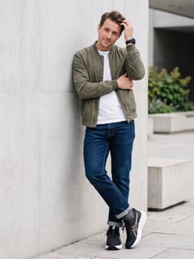 Athletic-fit slim indigo jeans styled with a premium heavyweight white cotton t-shirt and an unzipped olive bomber jacket for a street-ready look.