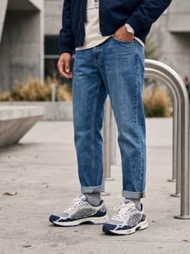 Light-wash distressed straight-leg jeans with a vintage-inspired oversized graphic tee and a navy nylon bomber jacket.