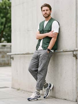 Grey tech-fleece joggers matched with a fitted white performance tee and a forest green utility vest for a functional gorpcore aesthetic.