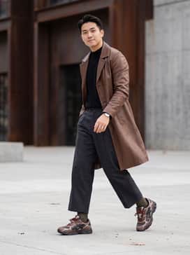 Gelnyc 20 Sshs – Wide-leg charcoal wool trousers paired with a black mock-neck sweater and a structured brown leather trench coat to emphasize the earthy tones.