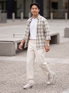 Baggy olive cargo pants, a tucked-in white boxy tee, and an unbuttoned cream flannel shirt for a relaxed streetwear vibe.