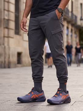 Gelresolution X – A sleek techwear-inspired outfit with charcoal tapered joggers, a black windbreaker, and a minimalist crossbody bag for a modern urban aesthetic.