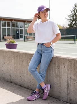 Gelresolution X – Tapered light-wash cropped denim jeans with a tucked-in oversized white graphic tee and a purple baseball cap.