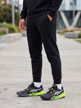 Gelresolution X – Tapered black tech-fleece joggers and a matching slim-fit hoodie, allowing the neon green midsole to serve as the outfit's primary focal point.