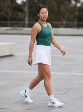 Gelresolution X – A performance-ready match look featuring a white pleated tennis skirt, a forest green moisture-wicking racerback tank, and white crew socks to highlight the sneaker's teal accents.