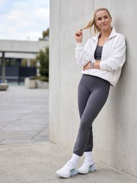 Gelresolution X – A sleek gym-to-street ensemble consisting of high-waisted charcoal leggings, a matching sports bra, and an oversized white quarter-zip sweatshirt.