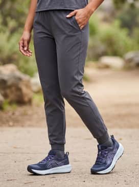 Tapered charcoal grey joggers, a crisp white cropped graphic t-shirt, and a lightweight navy blue puffer vest.