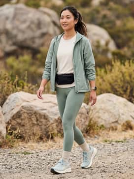 Gelsonoma 8 – High-performance sage green compression leggings and a matching sports bra, layered with a lightweight cream ripstop windbreaker for a cohesive athletic look.