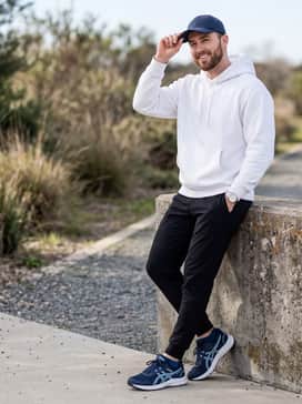 Gelventure 11 – Black tapered joggers combined with a crisp white oversized hoodie and a navy blue baseball cap for a modern, comfortable athleisure aesthetic.