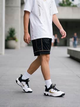 Black mesh basketball shorts and a white oversized graphic t-shirt with gold accents for a court-ready aesthetic.