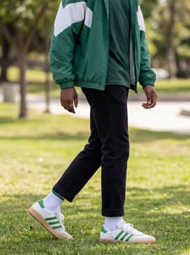 Black nylon track pants with a white side stripe, a fitted black performance tee, and a vintage-style windbreaker in matching green and white tones.