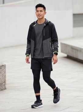 A high-performance technical look featuring black compression running tights, a moisture-wicking charcoal grey long-sleeve tee, and a lightweight neon-accented windbreaker for visibility.