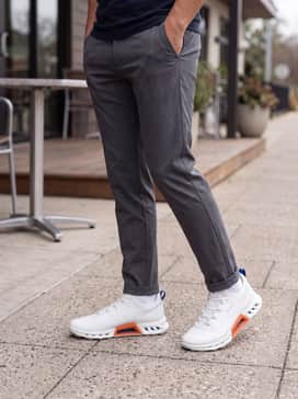 Golf Biom C4 – A refined weekend look with slim-fitting charcoal grey chinos and a premium white long-sleeved tee layered under a lightweight navy blue bomber jacket.