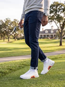 Golf Biom C4 – A smart-casual transitional attire with dark indigo tapered jeans worn with a light grey cashmere quarter-zip pullover over a crisp white collared shirt.