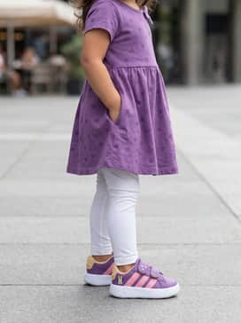 Grand Court Adidas X Disney Minnie Mouse Kids – A purple jersey skater dress with a subtle heart print, worn with white leggings and a matching pink bow headband to coordinate with the shoe's accents.