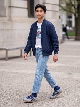 Light-wash straight-leg jeans with a white graphic tee featuring a vintage cartoon print and a navy blue bomber jacket.