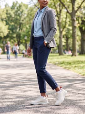 Slim-fit navy chinos rolled at the ankle worn with a light blue chambray button-down shirt and a structured grey blazer for a polished yet comfortable business-casual outfit.