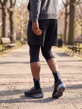 Gt Cut 4 – An intense training outfit featuring matte black compression leggings worn under loose-fitting charcoal shorts, topped with an oversized breathable performance hoodie.