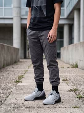 Gt Jump Academy – Street-ready ensemble with charcoal grey cargo joggers, an oversized heavy-weight black graphic t-shirt, and a silver chain accessory.