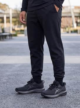 A relaxed weekend look featuring black tapered joggers, a fitted heather-grey hoodie, and a simple black baseball cap.