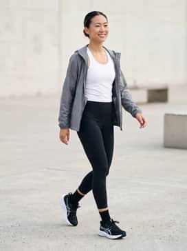 Gt1000 14 Wide – High-waisted black compression leggings paired with a breathable white moisture-wicking racerback tank and a lightweight grey windbreaker for a dedicated workout session.