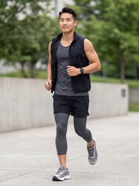 A technical moisture-wicking black tank top paired with charcoal grey compression tights and a lightweight running vest for optimal temperature control during long runs.