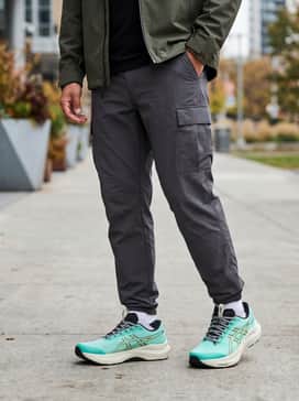 A gorpcore-inspired street look with charcoal-colored technical cargo pants, a black base-layer turtleneck, and a mustard yellow rain shell jacket to play off the shoe's accents.