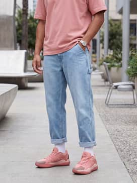 A streetwear aesthetic with oversized light-wash baggy denim jeans, a white boxy graphic tee, and a matching rose pink beanie.