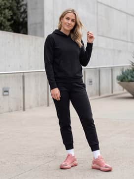 A sleek athleisure outfit consisting of black tapered tech joggers, a fitted black performance hoodie, and high-performance crew socks in white.