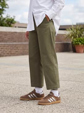 Olive green wide-leg chino trousers and a crisp white oversized button-down shirt for a sophisticated yet relaxed earth-toned ensemble.