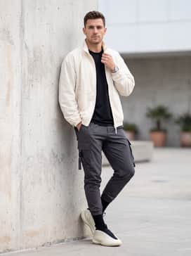 Tapered charcoal cargo pants with utility straps and a cream-colored oversized windbreaker to complement the shoe's palette.