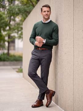 Helsinki 2 – Charcoal grey dress trousers accompanied by a forest green merino wool sweater over a white collared shirt for a sophisticated autumnal vibe.