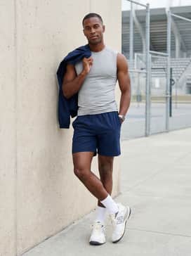 Navy blue athletic shorts combined with a light grey sleeveless compression shirt and a sleek, technical windbreaker for pre-game warm-ups.