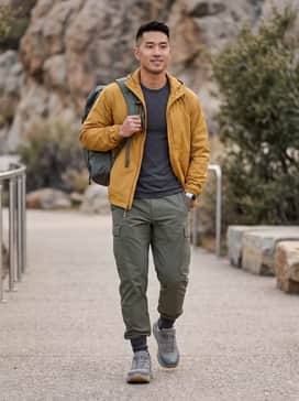 Technical olive green cargo pants paired with a moisture-wicking charcoal base layer and a lightweight mustard rain shell for a functional hiking look.