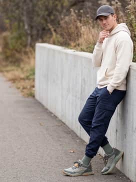 Tapered navy joggers combined with a cream-colored heavyweight hoodie and a structured neutral-toned baseball cap for a relaxed weekend vibe.