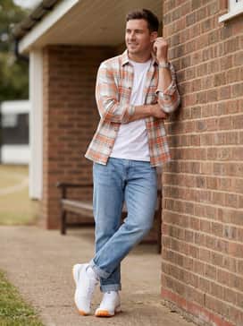 Light wash slim-fit denim jeans with a cuffed hem, a crisp white organic cotton t-shirt, and an open orange-toned plaid shirt for a relaxed post-game look.