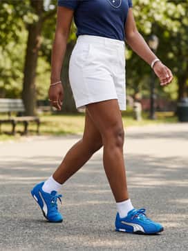 Hstreet Track  Field – White high-waisted chino shorts and a tucked-in navy blue polo shirt with delicate silver jewelry for a polished, preppy summer vibe.