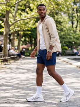 Hyper Speed 5 – A summer-ready sporty look with navy blue mesh athletic shorts, a breathable white tank top, and a lightweight nylon windbreaker in a neutral tone like sand or olive.